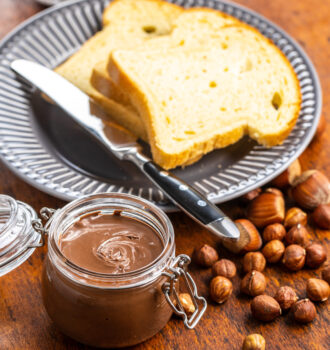 Hazelnut spread and toast bread. Chocolate cream on wooden table.